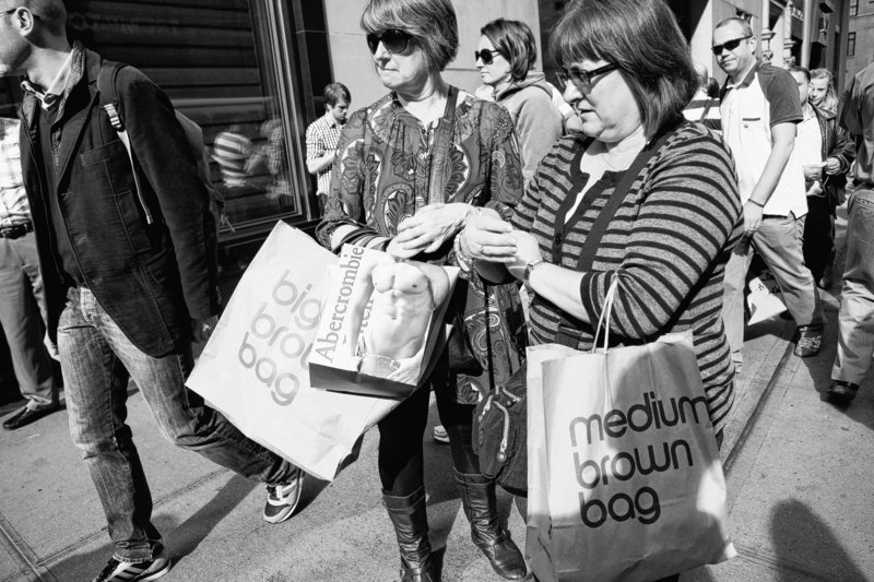 Women carry shopping bags on Fifth Avenue in New York. The economy grew at a slightly faster pace over the summer as Americans spent more, the Commerce Department said.
