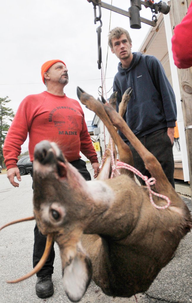 Matt Flaherty of Hollis, left, watches the scale while weighing his deer as Corey Hart of Lyman looks on at Merrill s Country Store in North Waterboro on Saturday, opening day for the deer-hunting season.