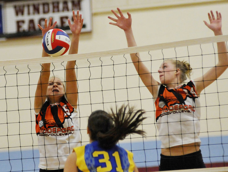 Bailey Cote, left, of Biddeford goes high for a block with help from Alyssa Drapeau during the Class A volleyball state final Saturday against Falmouth at Windham High. The top-ranked Tigers clinched their first title with a 3-0 win.