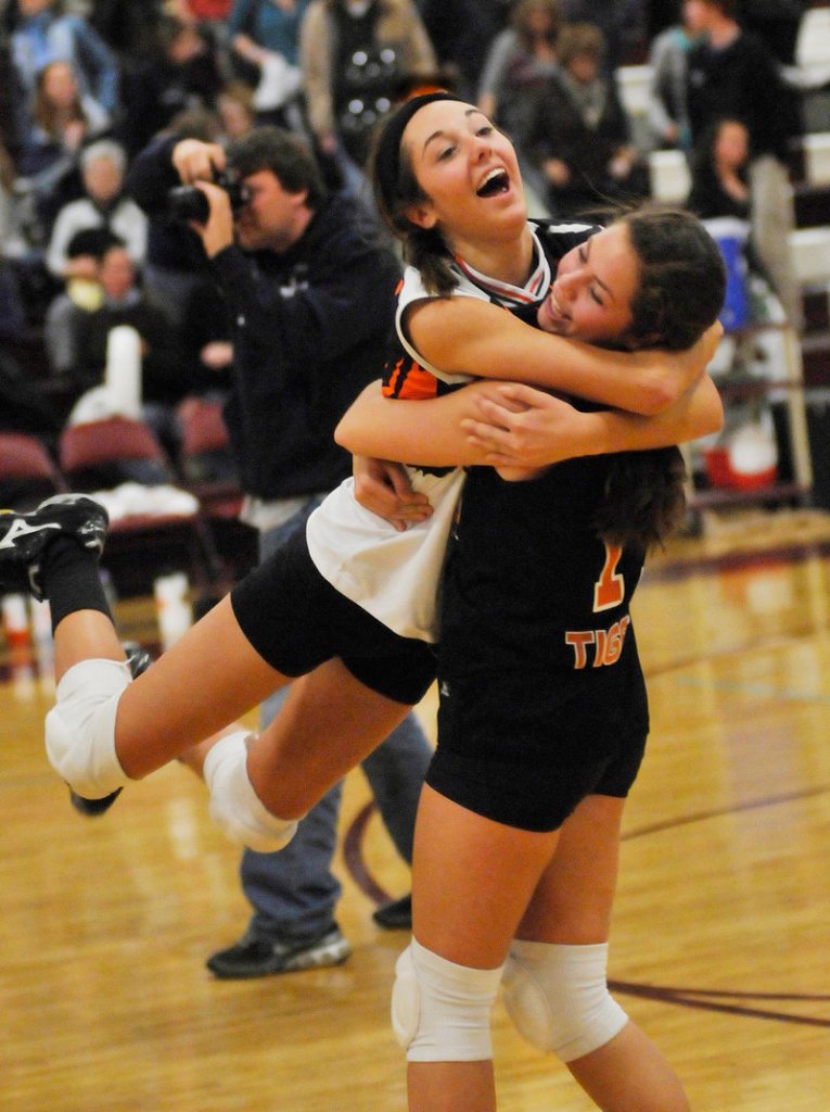 Renee Trottier leaps into the arms of teammate Katelyn Lebreux as they celebrate a victory over Falmouth in the Class A volleyball state final Saturday at Windham High School.