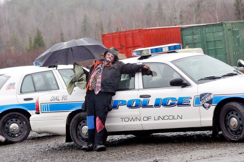 Staff Photo by Shawn Patrick Ouellette: Protester Don Thomas of Lincoln who dressed as a clown named Scruffy stands near a police car as police were arresting protesters who blocked construction vehicles at the Rollins wind energy project in Lincoln Monday, Nov. 8, 2010. Thomas was with Friends of Lincoln Lakes.
