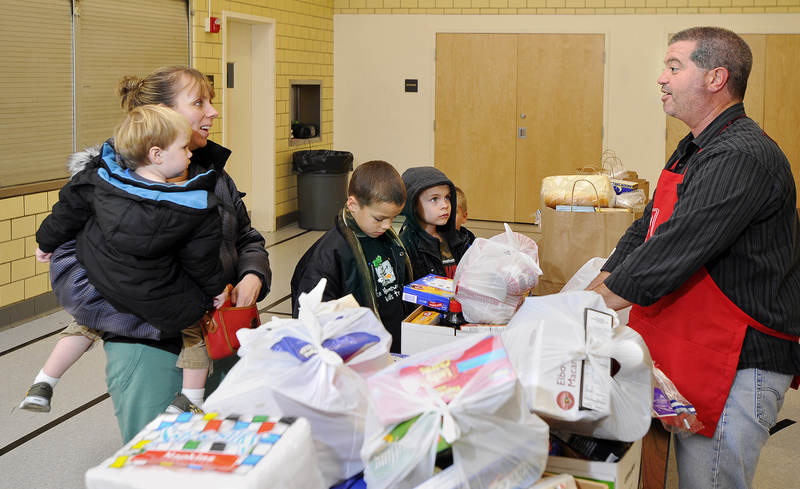 Volunteer David Menard chats with Gloria Dennison as she and her children pick up Thanksgiving food donations at the Salvation Army building on Cumberland Avenue in Portland on Monday.