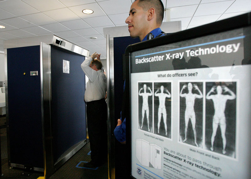 In this photo taken Sept. 1, 2010, Transportation Security Administration employee Anthony Brock, left, demonstrates a new full-body scanner at San Diego's Lindbergh Field, with TSA employee Andres Lozano in San Diego. The American Civil Liberties Union has denounced the machines as a "virtual strip search." Across the country, passengers must choose scans by full-body image detectors or probing pat-downs. Top federal security officials said Monday, Nov. 15, 2010, that the procedures were safe and necessary sacrifices to ward off terror attacks. (AP Photo/San Diego Union Tribune, Eduardo Contreras)
