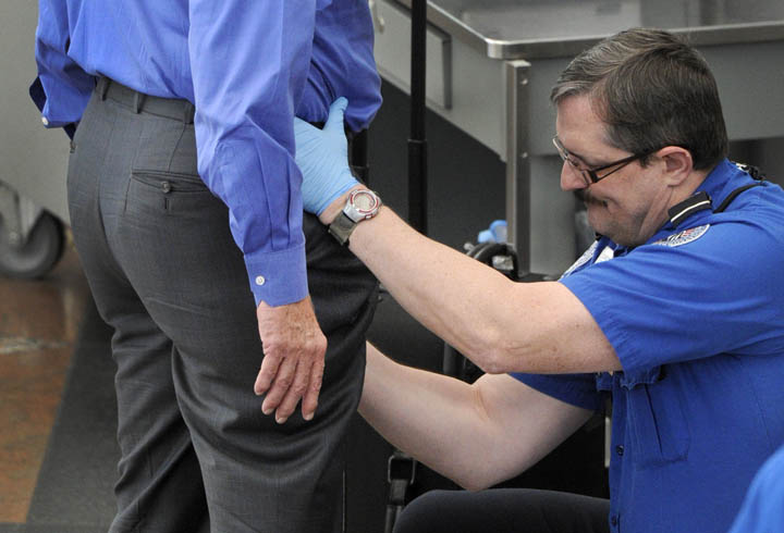 A Transportation Security Administration agent performs an enhanced pat-down on a traveler at a security area at Denver International Airport recently.