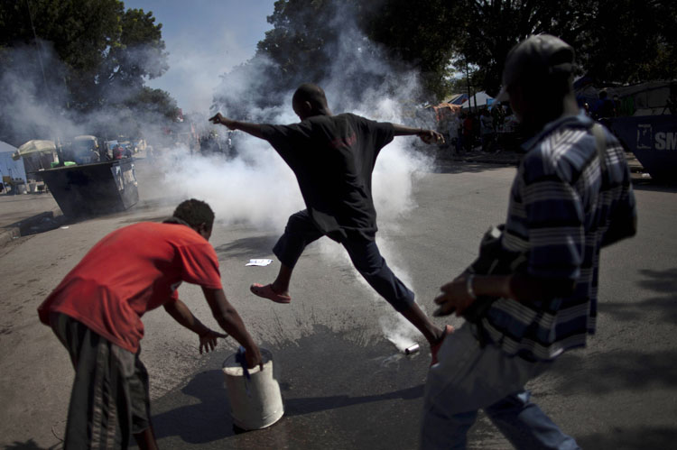 A demonstrator runs to avoid tear gas fired by police and UN soldiers during a protest in Port-au-Prince, Haiti, Thursday,. Following days of rioting in northern Haiti over suspicions that U.N. soldiers introduced a cholera epidemic that has killed more than 1,000 people, protesters in Haiti's capital clashed with police, lashing out at U.N. peacekeepers and the government, blocking roads and attacking foreigners' vehicles.