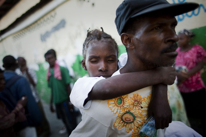 A young woman suffering cholera symptoms is carried by a relative to St. Catherine hospital, run by Doctors Without Borders, in the Cite Soleil slum of Port-au-Prince today. Thousands of people have been hospitalized for cholera across Haiti with symptoms including serious diarrhea, vomiting and fever and at least 1,100 people have died.