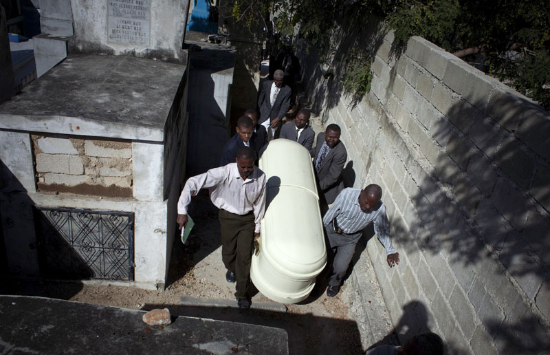 Relatives of Serge Ragmond, 49, who died of cholera, carry his coffin during his burial at the cemetery in Port-au-Prince today.