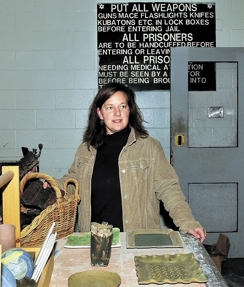 Amber Lambke, owner of Somerset Grist Mill in the former Somerset Jail in Skowhegan, speaks about a pottery venture in the sally port where prisoners were transported and a sign in background advised jail personnel to remove their weapons before entering jail.