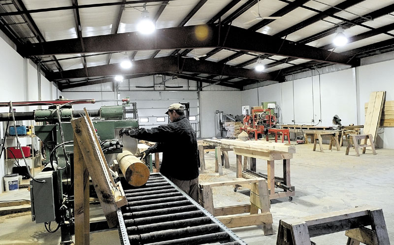 Roland McKenna operates a rebuilt saw Wednesday at the new mill building at Hilltop Log & Timber Homes in Sidney. Fire destroyed the original building last May.