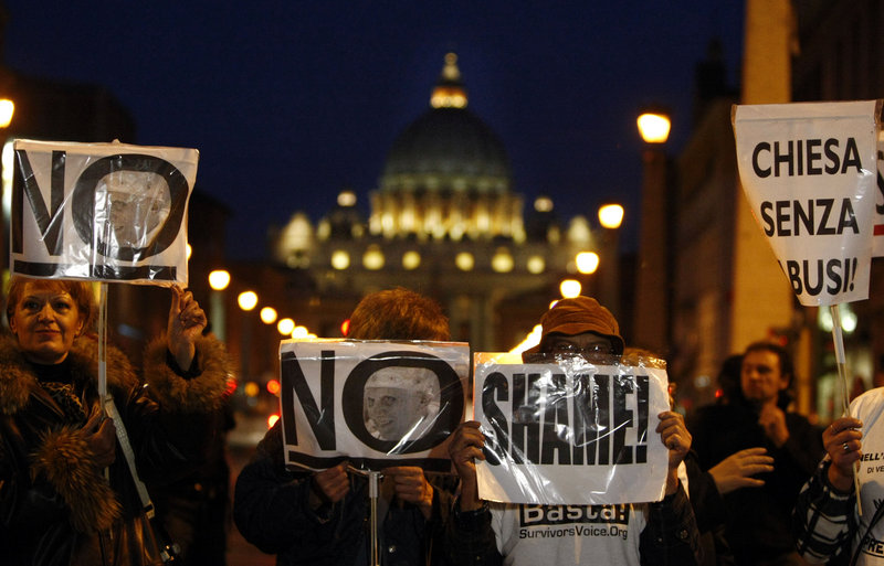 Demonstrators hold placards Sunday in Rome. Italian paramilitary police blocked a boulevard to prevent a march by sex-abuse survivors from reaching St. Peter’s Square.
