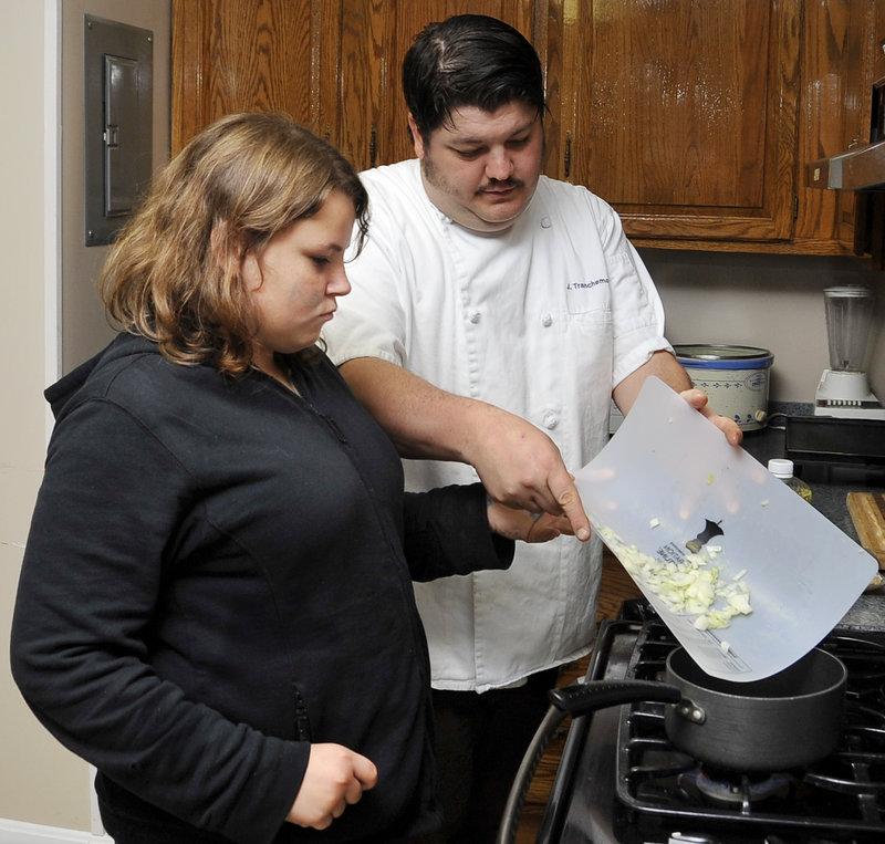 Chef James Tranchemontagne and Amber Weitzell, 12, add the onions to a marinara sauce.