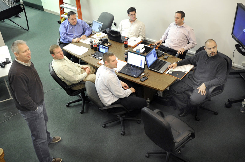 Celtics President Danny Ainge, standing, oversees the Red Claws draft Monday night at the club's offices. Maine GM Jon Jennings is at the left end of the table. Seated, clockwise, are Chris Sellos, Coach Austin Ainge, Hernando Planells, Cam Twiss and Jay O Connell.