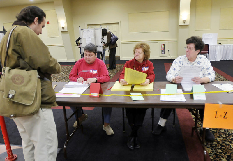 Election clerks Gail Hannon, left, Erlene Stuart and MaryAnn Morin are ready to check in voters, including Cory Lasala, far left, at the Italian Heritage Center in Portland on Tuesday.