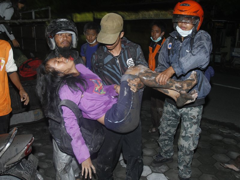 Villagers carry a woman as they flee their homes following another eruption of Mount Merapi in Klaten, Indonesia, today. A new eruption at Indonesia’s volcano has forced authorities to widen the “danger zone” to 12 miles from the fiery crater.