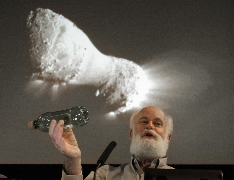 Michael A’Hearn uses a plastic bottle to describe the rotation of the comet Hartley 2 beneath an image made from NASA’s Deep Impact spacecraft, which passed within 435 miles of the comet, at the Jet Propulsion Laboratory in Pasadena, Calif., on Thursday.