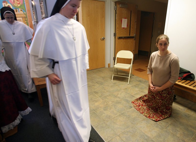 Andrea Bowers, 16, kneels in the hallway of the chapel at Spiritus Sanctus Academy in Ann Arbor, Mich., as members of the Dominican Sisters of Mary, the order that runs the school, proceed to receive communion during Mass. In sharp contrast to many other congregations, the conservative order is growing rapidly, and the average age of its 113 members is 26.