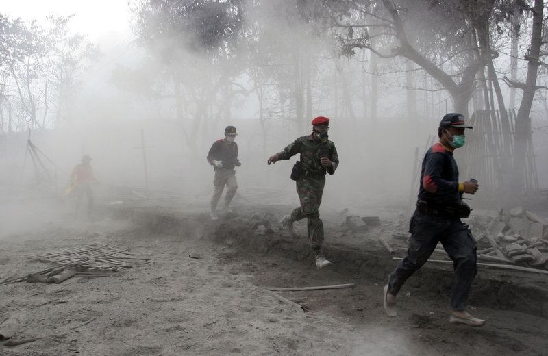 An Indonesian solder and rescuers run after an eruption of Mount Merapi in Indonesia on Friday. The danger zone has been expanded to a ring 12 miles from the mountain’s peak.