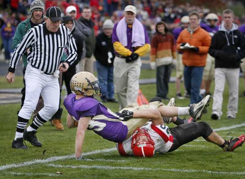 Jack Bushey of Cheverus is dragged down by Scott Thibeault of Scarborough after catching a fourth-and-7 pass that brought the ball to the Red Storm 7. The unbeaten Stags went on to score the winning touchdown and reach the Western Class A final with a 21-14 victory.