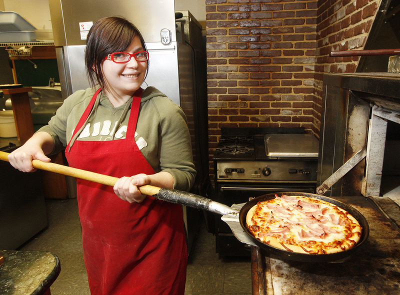 Janelle Bavota pulls a pie out of the oven at Pizza Villa in Portland.