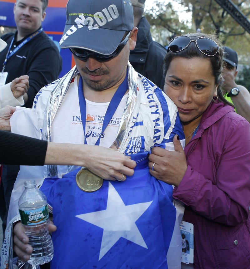 Angelica Alvarez, right, the wife of Chilean miner Edison Pena, embraces her husband after he crossed the finish line of the New York City Marathon on Sunday. Pena said training for the race in darkness during his 69 days underground was his salvation.
