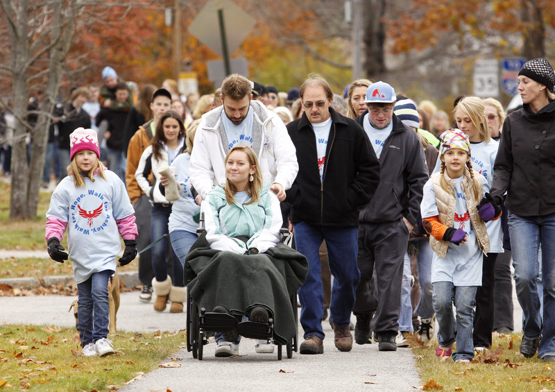 Hundreds of people participate in a walk in Kennebunk on Sunday in support of high school senior Ashley Dubois, who was injured in a car crash in September. Ashley, whom doctors doubted would walk again, started and ended the event walking with a metal walker. For most of the route, she led the way in a wheelchair pushed by her brother Matt Dubois.
