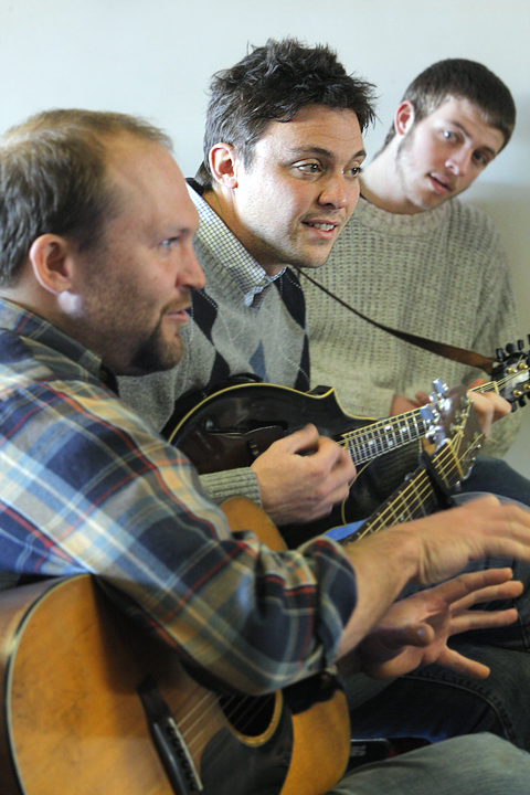 Andrew Martelle, center, strums on his mandolin Monday while listening to a song created by students at Casco Bay High School. Martelle and Matt Shipman, left, from 317 Main St music center, are helping students at the school develop their songs and performance skills. At right is senior Cam Finn.