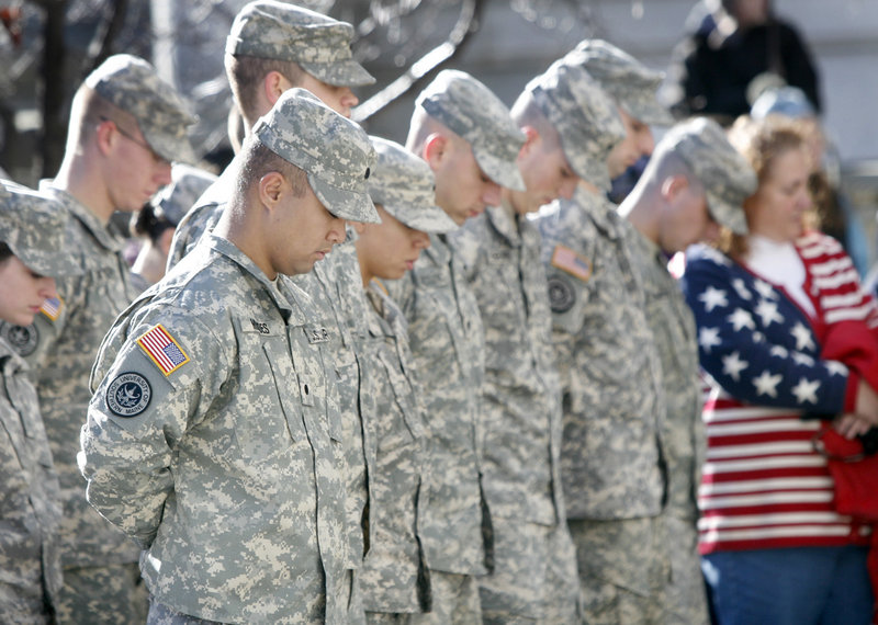 Members of the University of Southern Maine Army ROTC, who helped lead the parade, bow their heads during the playing of taps after the laying of the wreaths ceremony at City Hall.