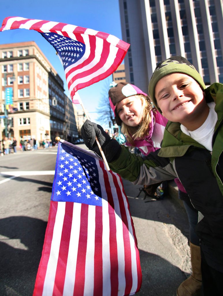Emma Letarte, 9, and Sam Letarte, 8, who live in Scarborough, take a look down Congress Street in Portland on Thursday, hoping to see evidence that the Veterans Day parade has begun.