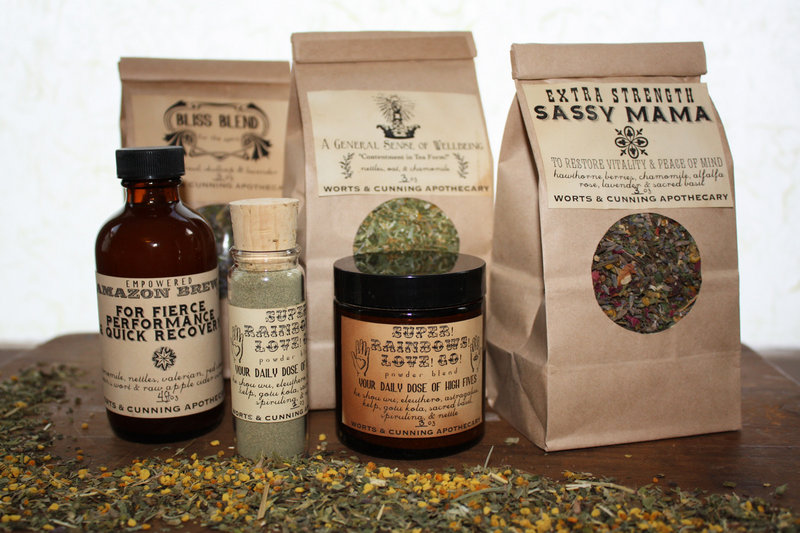 Worts & Cunning Apothecary herbal products include Bliss Blend tea, A General Sense of Wellbeing tea, Sassy Mama tea, Empowered Amazon Brew vinegar, and Super! Rainbows! Love! Go! herbal powder.