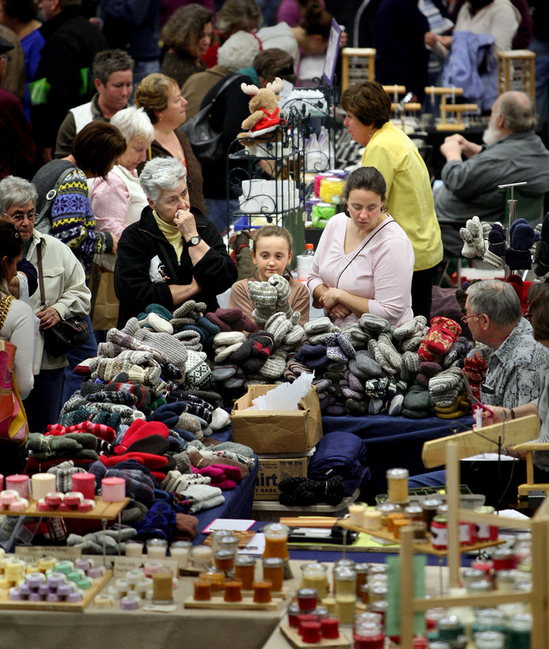 Katie Brittain, 9, of Farmington tries on mittens with her grandmother Babe Edgar of Jackman, left, and her mother, Denise Brittain of Farmington, at the Mitchy's Mittens booth during the Augusta Arts and Crafts Show at the Augusta Civic Center on Saturday. Mitchy's Mittens are made from the yarn of sweaters from Goodwill.