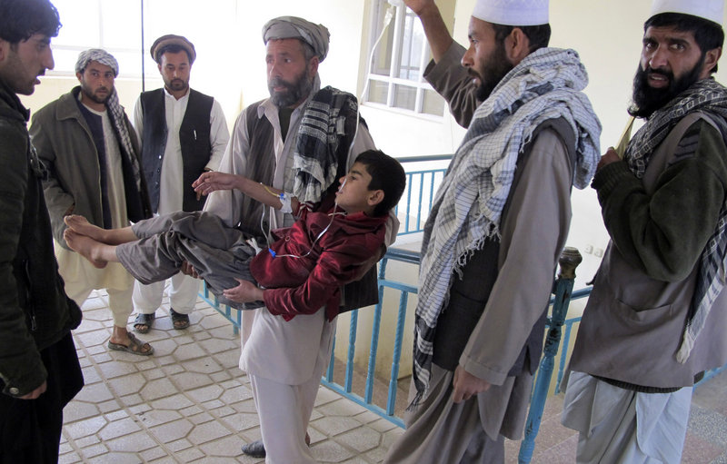 An Afghan man carries a boy who was wounded in an explosion in Kunduz, Afghanistan, on Saturday. Ten people including three children died in the attack.