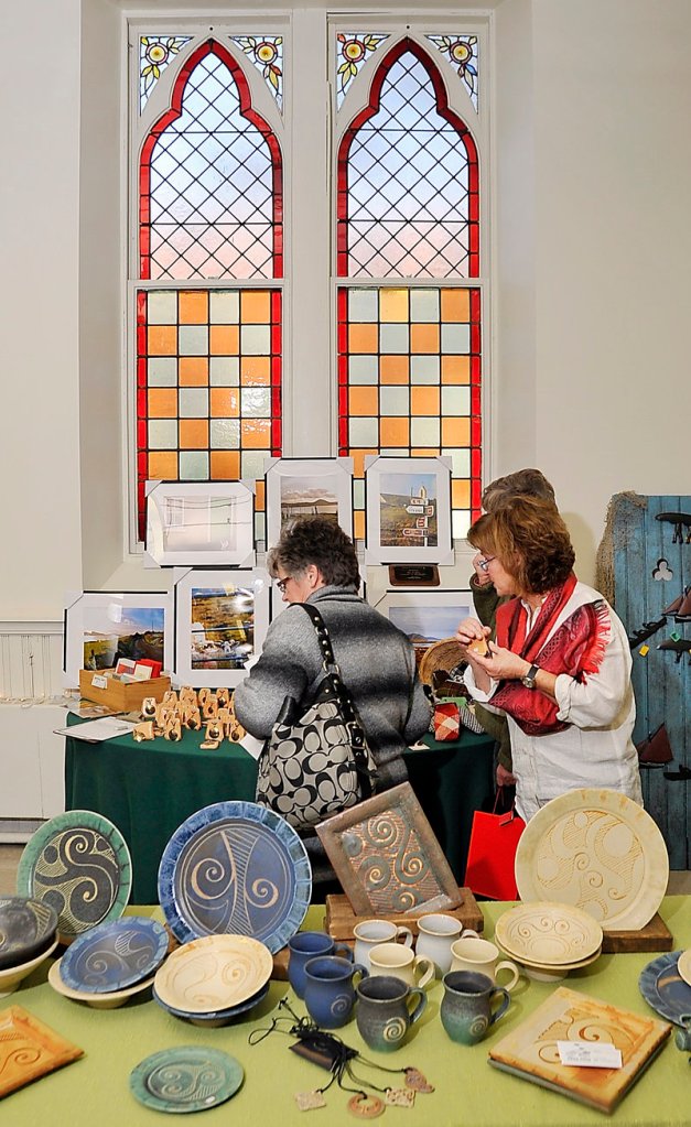 Colleen Boland, right, helps customers looking at her collection of items from Ireland at the craft fair.
