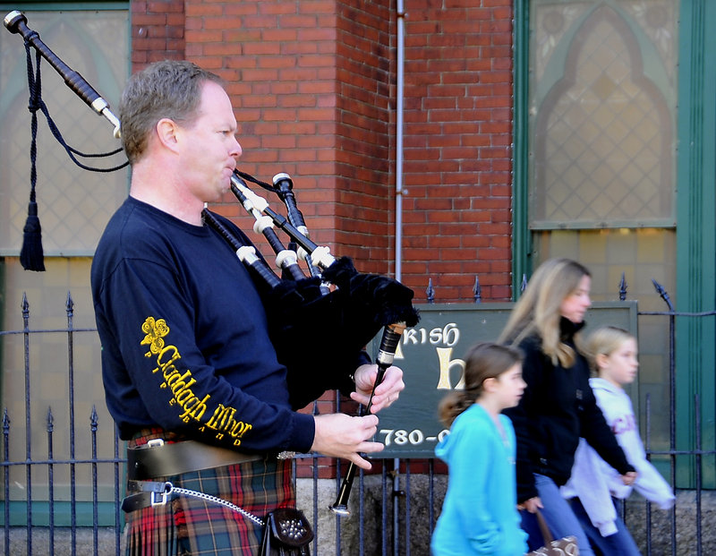 Tom Ryan plays bagpipes as Catherine Cornell and daughters Caitlin, 9, left, and Anna, 7, all from Cape Elizabeth, head into A Celtic Christmas, a craft fair at the Irish Heritage Center.