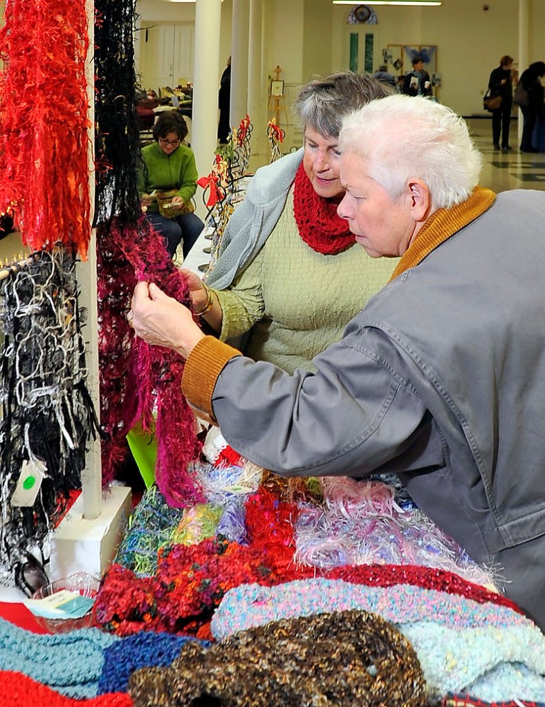 Rita Thompson of South Portland, right, inspects the handcrafted “Magic Laces” and Mobius cowls made by artist Jean Maiorano, left, at the craft fair.