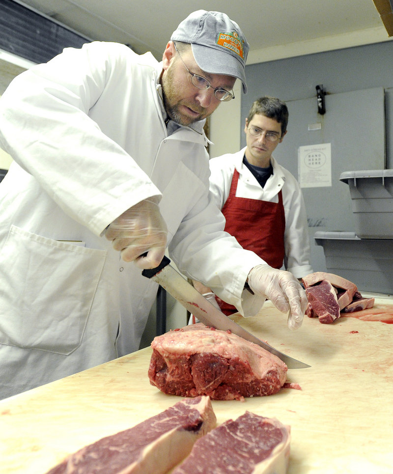 Meat manager Chris McCourt, right, watches reporter Ray Routhier cut meat.