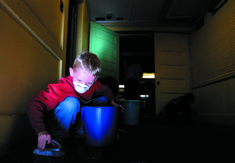 Friedrick Wilcox, 9, of Fairfield scrubs the entryway floor at the First Baptist Church in Waterville on Thursday afternoon. Volunteers are helping to prepare the space so homeless people can sleep in the basement starting Dec. 1.