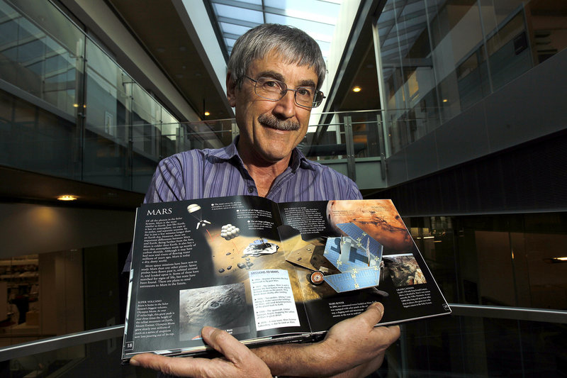 Dr. Paul Davies of Arizona State University holds a book on Mars as he stands in the atrium of the Biodesign Institute building on the ASU campus.