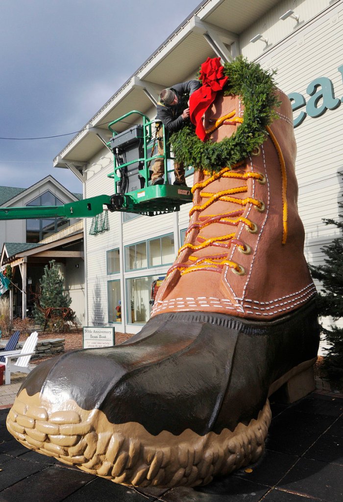 Jesse LaCasse of Pandora LaCasse Design puts up a wreath on the boot during the L.L. Bean Northern Light Celebration in Freeport Saturday.