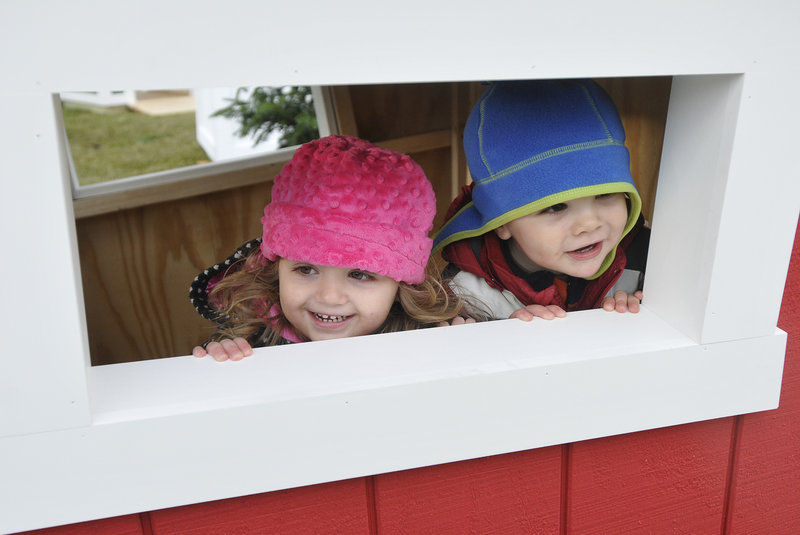 Emily Nicoll, 2, of Fredericton, New Brunswick, and Declan Byrne, 2, of Hartford, Conn., peek out the window of a crooked wooden house during the Northern Light Celebration.