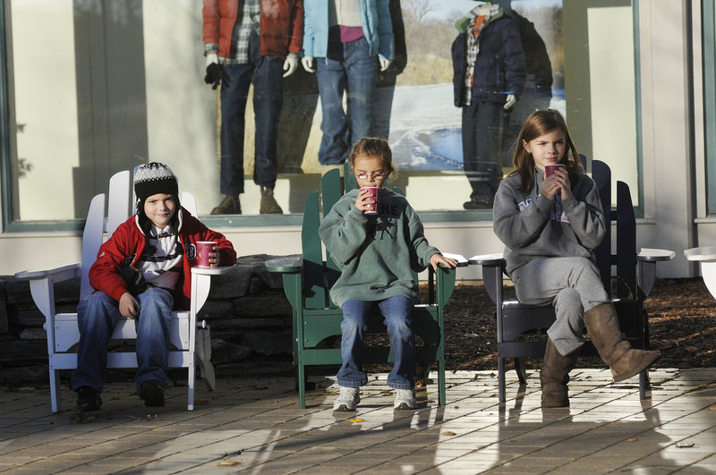 From left, Daniel Forester, 8, Christina Forester, 7, and Stephanie Forester, 11, all of Walpole, Mass., enjoy free hot cocoa as they sit in Adirondack chairs outside L.L. Bean during the Northern Light Celebration Saturday.