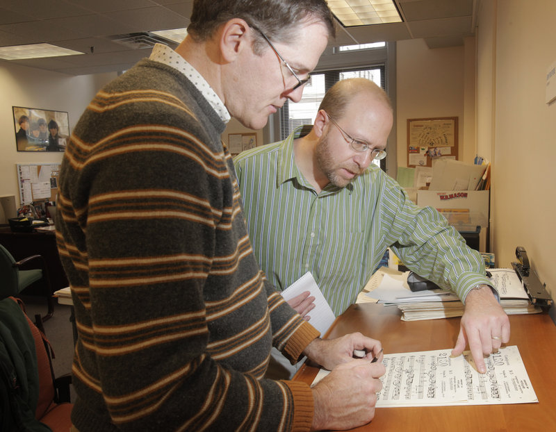 Reporter Ray Routhier looks over sheet music with Jon Poupore, left, librarian for the Portland Symphony Orchestra.