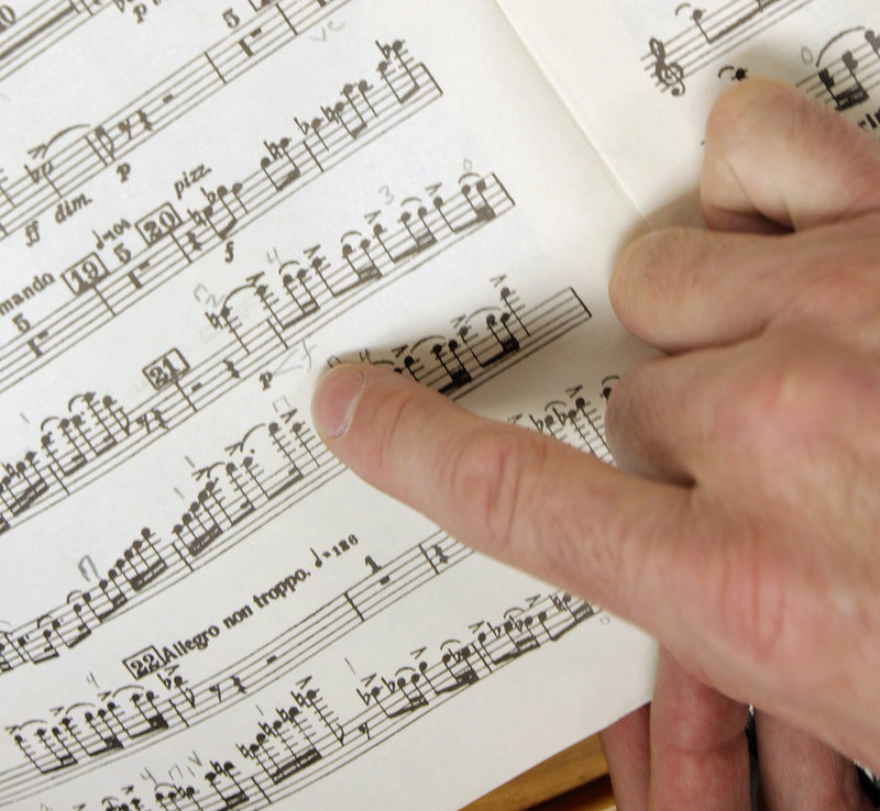 Jon Poupore, Portland Symphony Orchestra librarian, reviews violin sheet music for marks telling the musicians when to raise and lower their bows, so they are in unison.