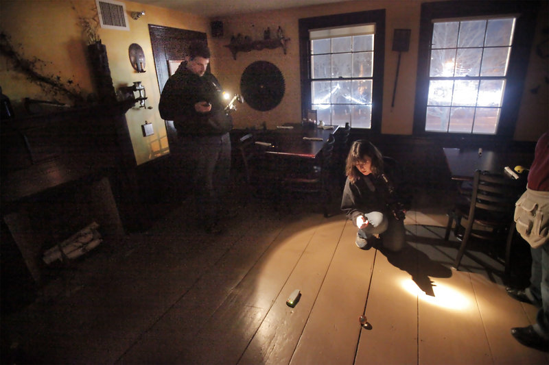 Jennifer Elliott, center, and James Logsdon, left, watch an electromagnetic frequency meter and a ball on the floor as they search for paranormal activity at the Maine Street Grill.