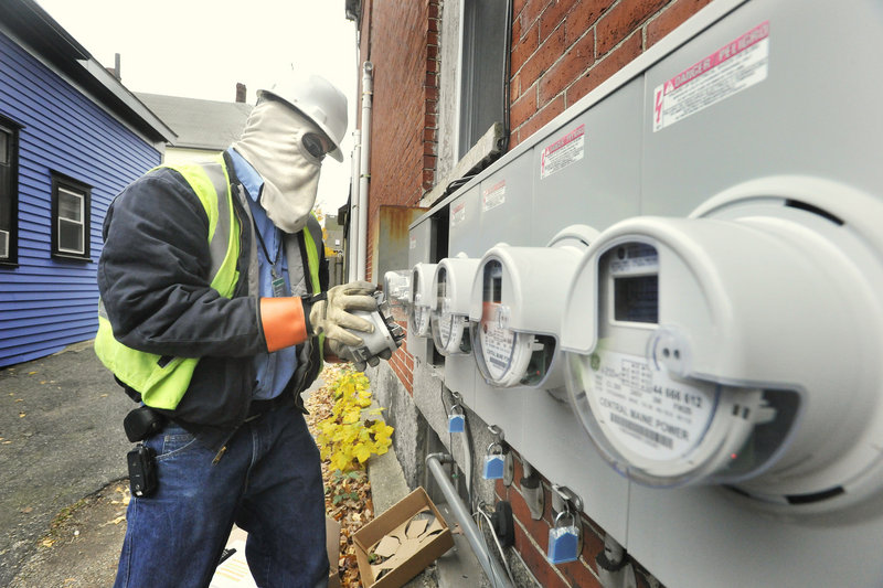 Zach Pomelow, wearing face and hand safety equipment, installs new smart meters at homes on Brackett Street in Portland.