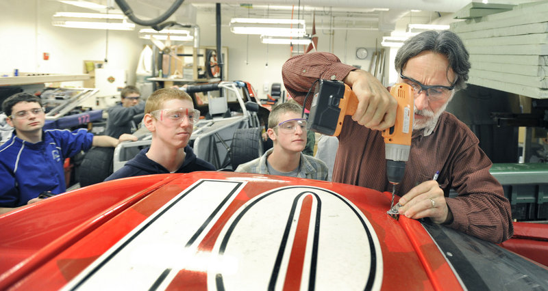 Instructor John Kraljic, right, leads a Falmouth High School advanced engineering class that’s designing and building an electric race car. “I absolutely love building and machining stuff,” said senior Sarah Collmus, one of three girls in the class. “I can’t wait to drive one of the cars.”