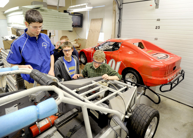 Joe Conway, left, Jamie McCatherin and Tim Follo, right, examine one of the race cars their advanced engineering class is working on. The gas-powered car will race the electric one in a later stage of the class’s work.