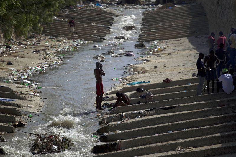 A man bathes in a canal filled with garbage in Port-au-Prince, Haiti, on Monday.
