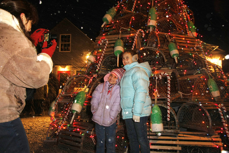 Karen Bonner of Plainville, Mass., takes a photo of her daughters, Jaclyn, 6, and Jessica, 10, in front of a lobster-trap Christmas tree at Sohier Park in York on Saturday.