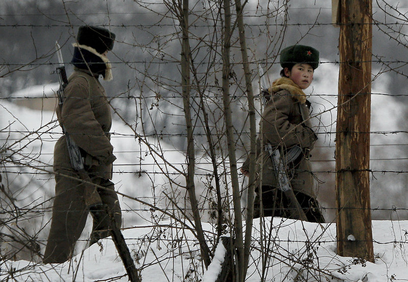 A North Korean female soldier, right, looks back Sunday as she and another patrol on a pathway along the bank of the Yalu River, the China-North Korea border river, near North Korea’s town of Sinuiju, opposite the Chinese border city of Dandong.