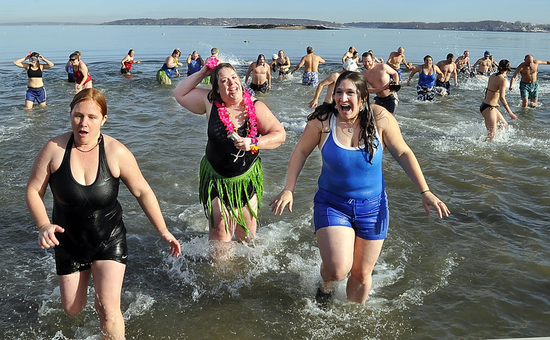 Stacie Haines, left, Beth Dimond and Elisa Doucette scurry from the water as fast as they went in Friday after realizing how cold the water was during the Natural Resources Council Polar Bear Plunge at East End Beach in Portland.